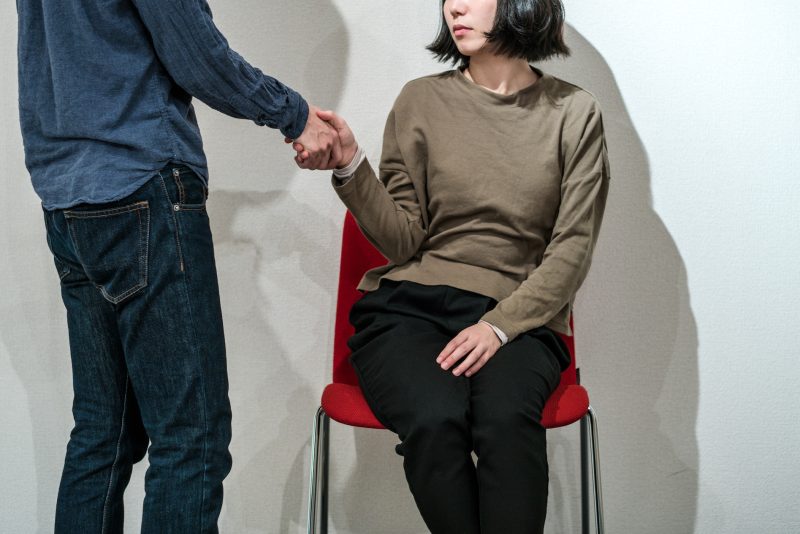 椅子に座っている女性と手を繋ぐ男性