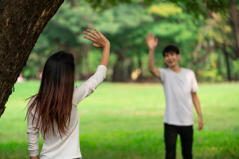 木の下で手を振る男女