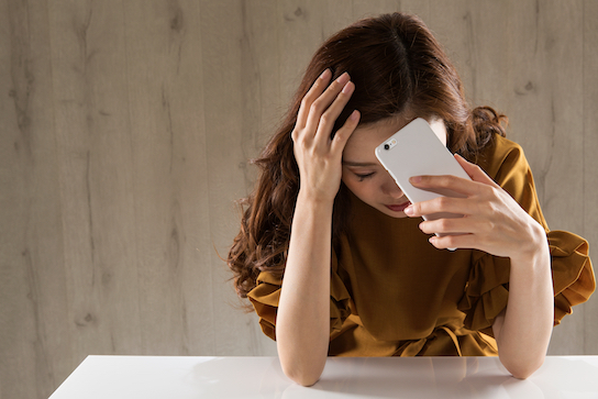 スマホを持って悩む女性