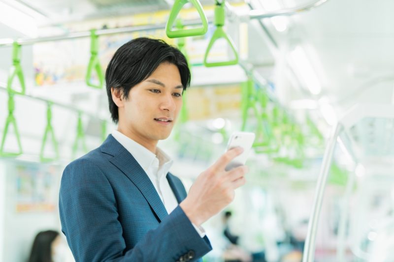 電車に乗ってスマホを触る男性