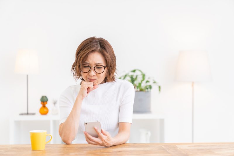 スマホを見て考えごとをする女性